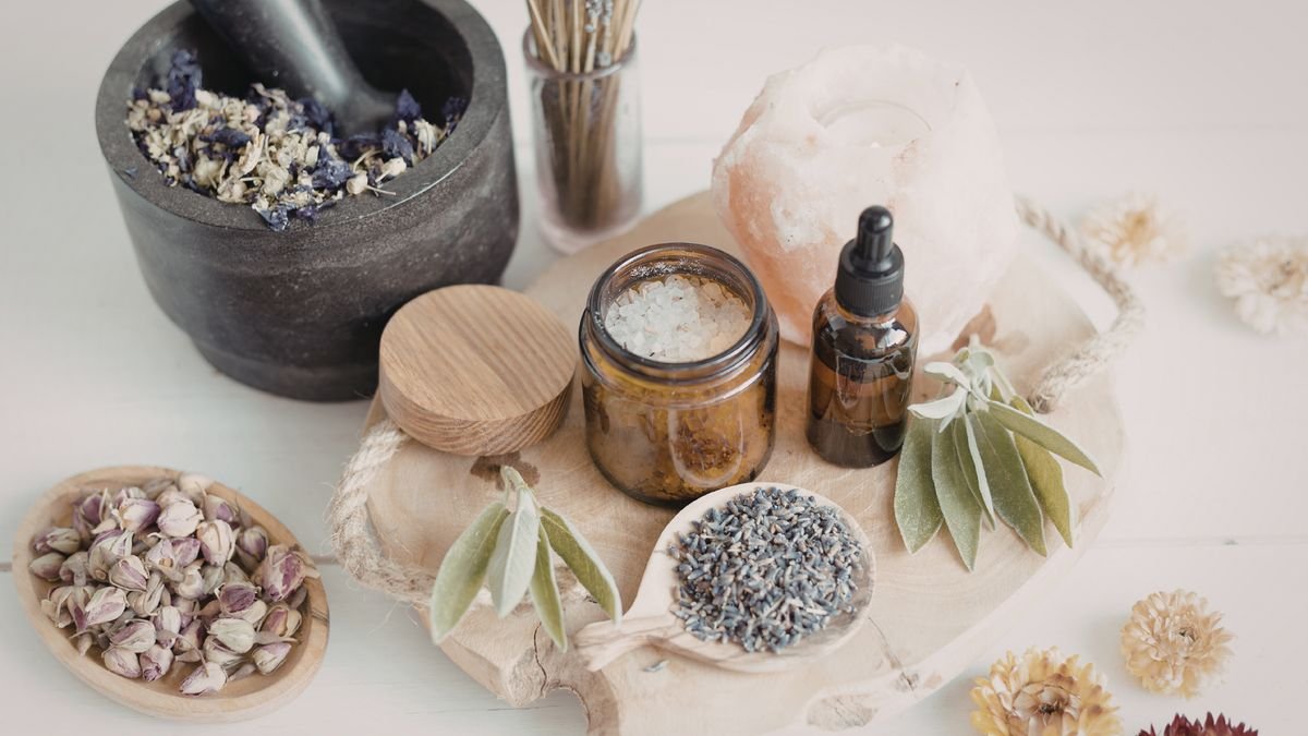 Mortier de pierre, huiles essentielles, lavande et boutons de rose séchés sur une planche en bois